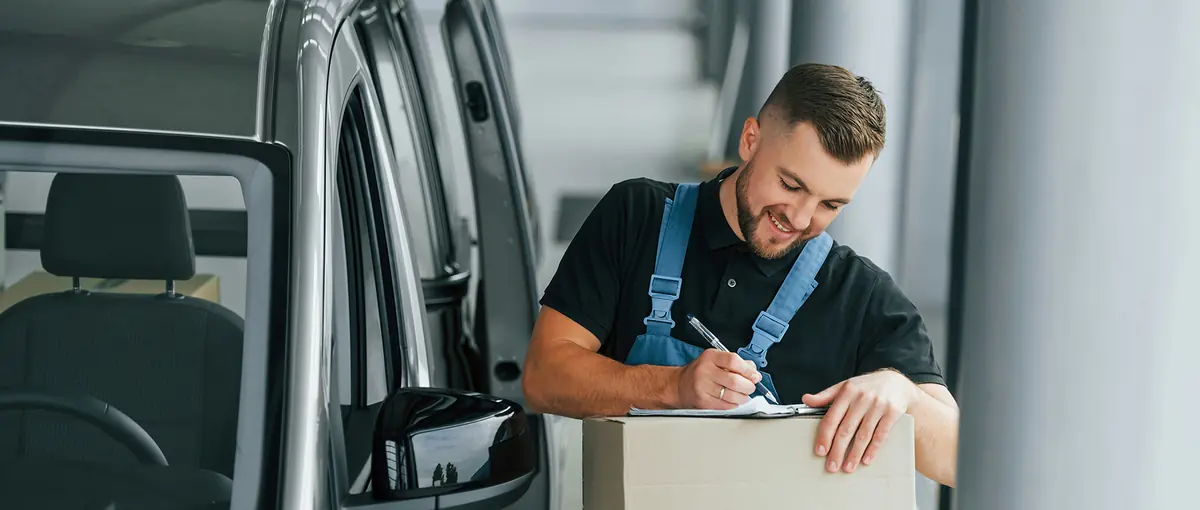 A tradesman with a clipboard beside his van