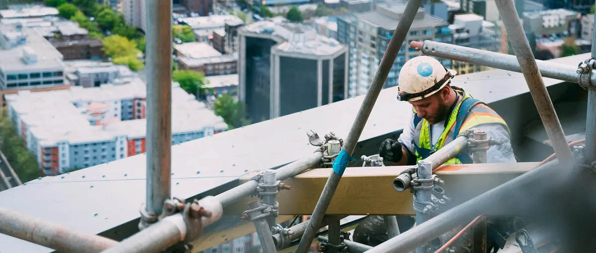 A construction worker on scaffolding above the city