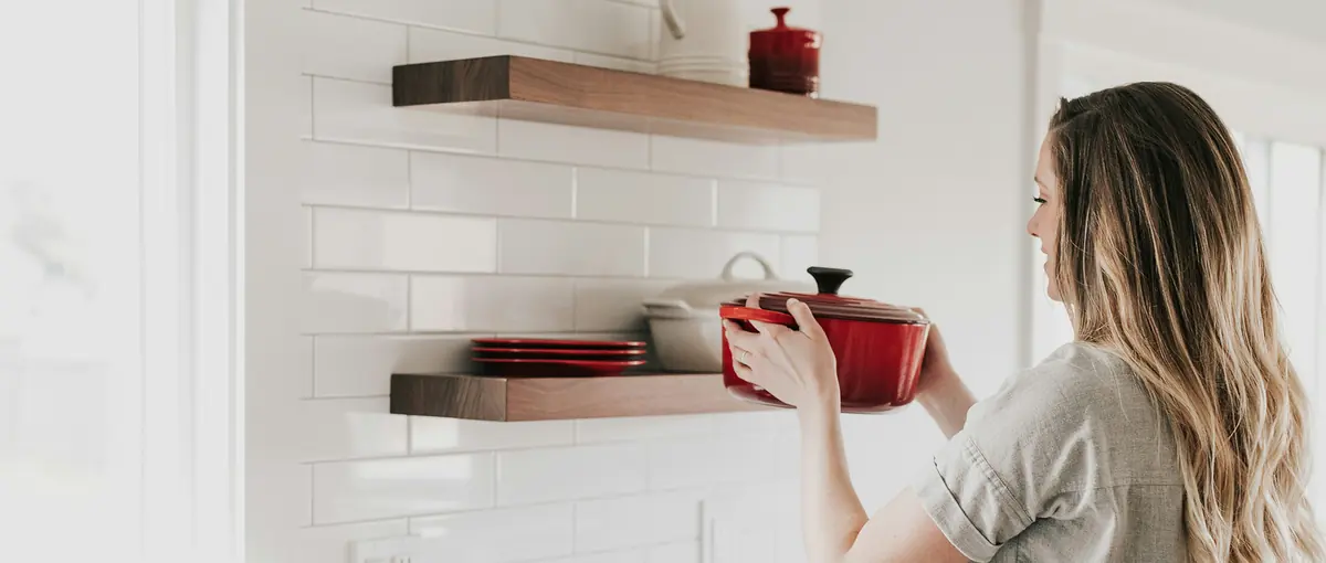 A woman unpacking a red pot in her new kitchen