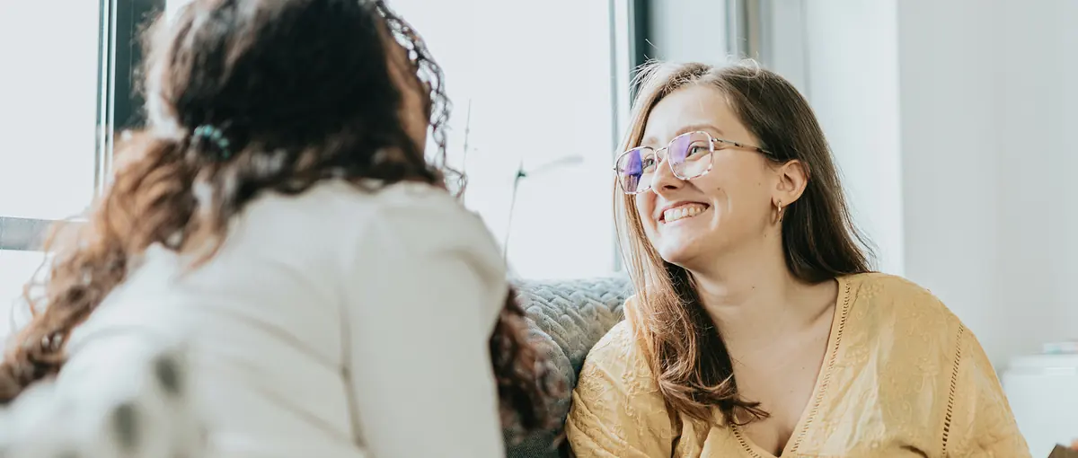 Two women laughing together on a couch