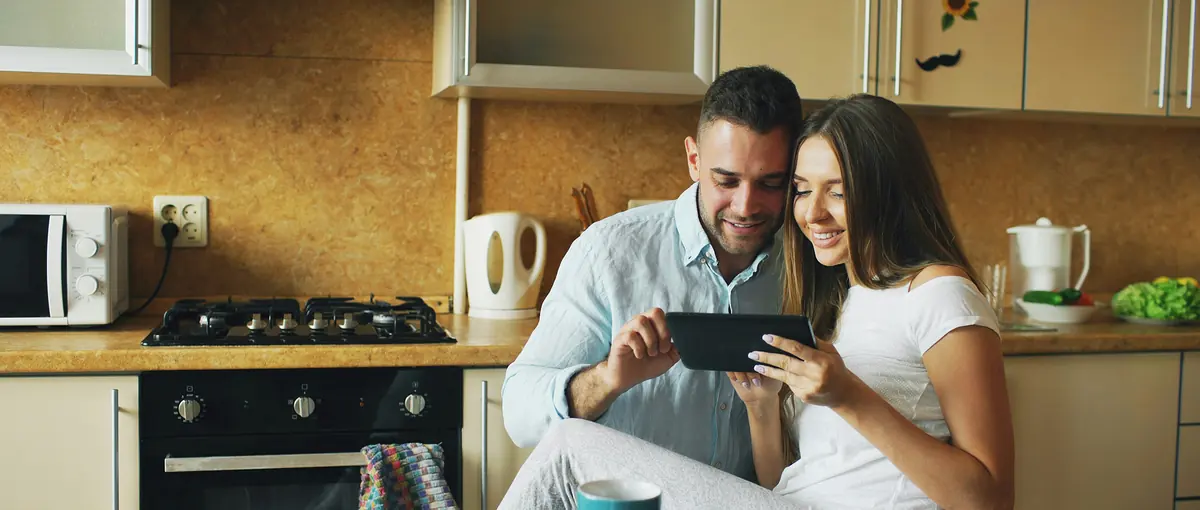 A couple looking at a tablet together in their kitchen